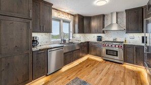 Una cocina moderna con armarios de madera oscura, electrodomésticos de acero inoxidable y piso de madera.