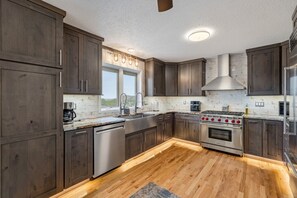 A modern kitchen with dark wood cabinets, stainless steel appliances, and a wooden floor.