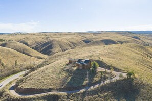 A house on a hill with a road curving around it. - Log cabin on a canyon, panoramic hills, 3 levels (Rapid City)