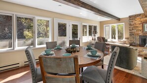 A dining area with a round table, chairs, and a stone fireplace. - Creekside Retreat | Fireplace + Gameroom (Rapid City)