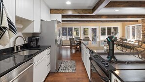 A modern kitchen with white cabinets, a black countertop, and a stove. - Creekside Retreat | Fireplace + Gameroom (Rapid City)