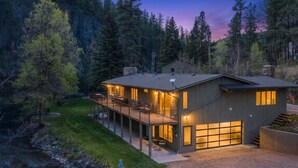 A modern two-story house with a deck, large windows, and a garage. - Creekside Retreat | Fireplace + Gameroom (Rapid City)