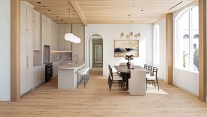 Une cuisine moderne avec des poutres en bois, un coin repas doté d’une table ronde et de grandes fenêtres.