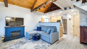 Un salon avec un canapé bleu, un téléviseur à écran plat et une cheminée.