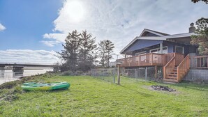 Une maison avec une terrasse, un kayak et une vue sur un plan d’eau.