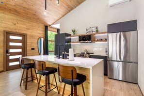Een moderne keuken met een centraal eiland, roestvrijstalen apparatuur en houten details.