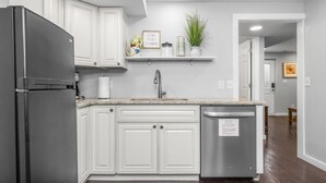 A modern kitchen with white cabinetry, a stainless steel refrigerator, and a dishwasher.