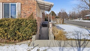 A residential house with a brick facade, a covered porch, and a snow-covered yard.