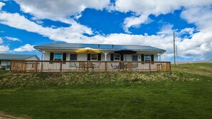 A single-story house with a porch, a fenced yard, and a clear sky.