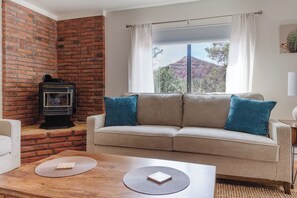 Ein Wohnzimmer mit Backsteinwand, einer blauen Kissensofa, einem Kamin und Blick durch ein Fenster.