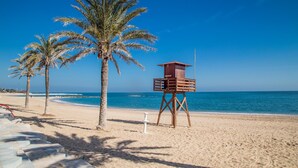 Uma praia com palmeiras e uma torre de salva-vidas.