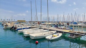 Uma marina com vários barcos atracados, um cais e um céu claro.