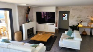 Un salon moderne avec une cheminée, un téléviseur à écran plat, des canapés blancs et une table basse.