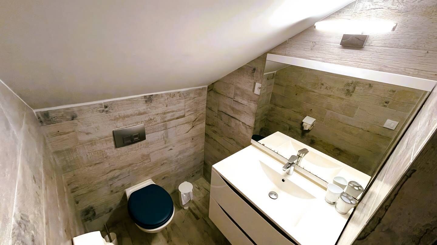 A bathroom with a wooden wall, a white sink, and a blue toilet.