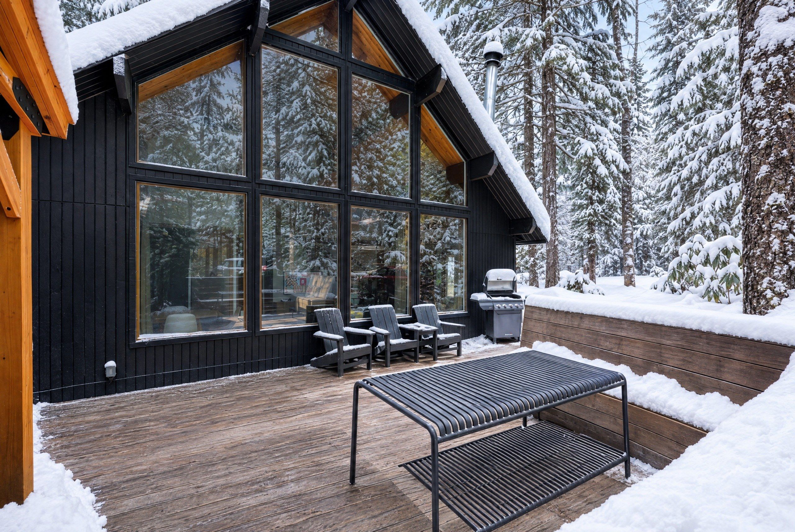 A modern wooden deck with a grill and outdoor seating.