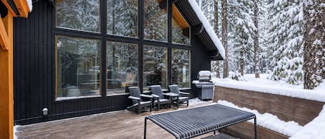 A modern wooden deck with a grill and outdoor seating.