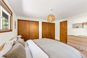 Un dormitorio con cama, armario de madera, cómoda y lámpara colgante.