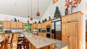 A modern kitchen with wooden cabinets, granite countertops, and stainless steel appliances.