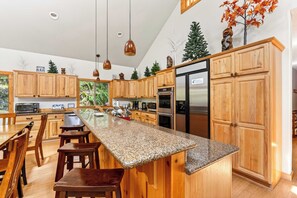 A modern kitchen with wooden cabinets, granite countertops, and stainless steel appliances.
