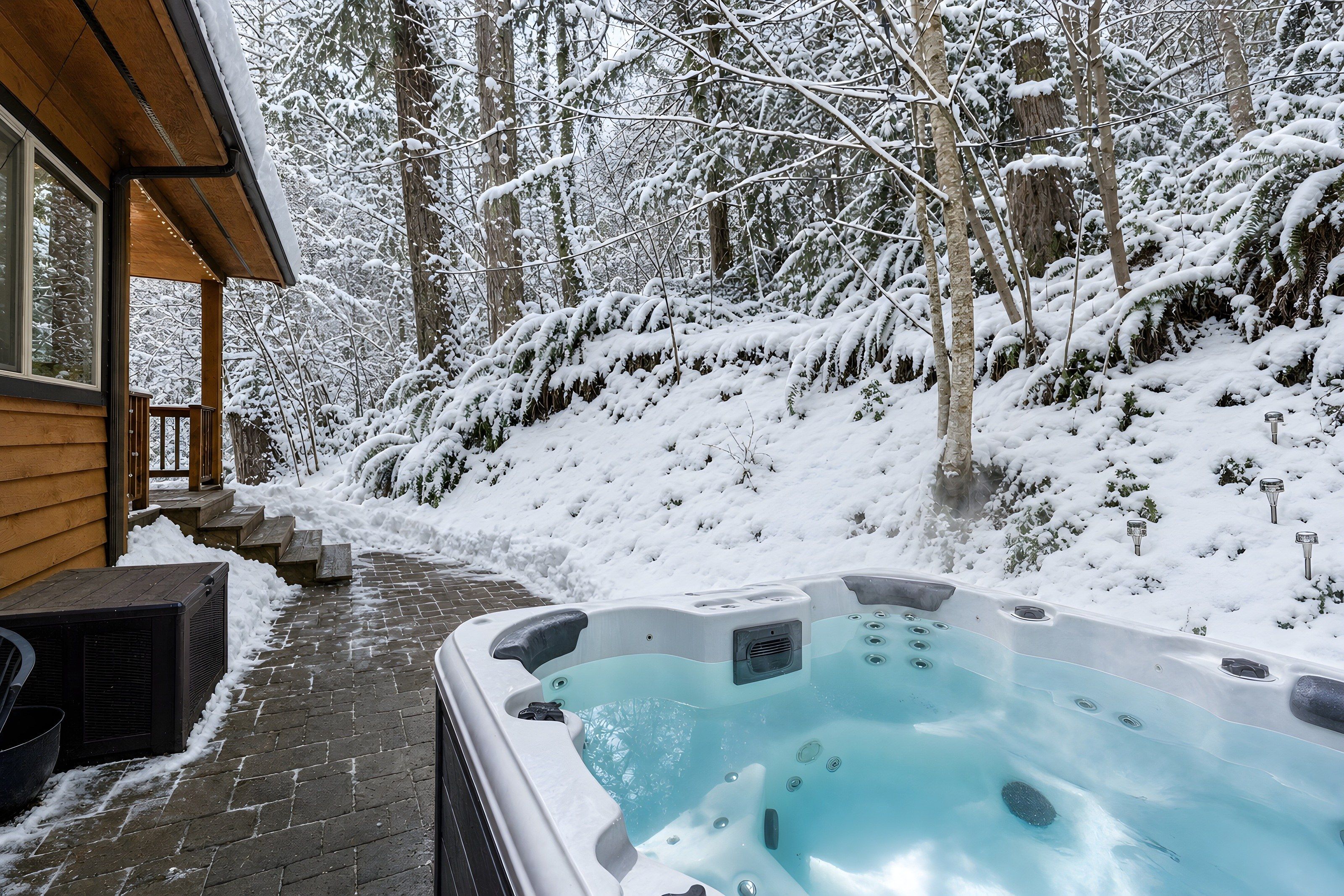 A wooden cabin with a hot tub on a snow-covered deck.