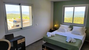 A bedroom with a bed, two windows, a desk, and a chair. - Domaine Pascialella, 20 pers, 3 piscines, vue mer (PORTO VECCHIO)