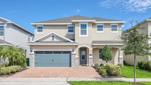 A two-story residential building with a garage, a front entrance, and a landscaped front yard. - Family Vacation Home Near Disney - Pool & Spa (Kissimmee)