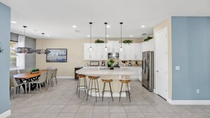 A modern kitchen with a central island, bar stools, and pendant lighting. - Family Vacation Home Near Disney - Pool & Spa (Kissimmee)