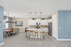 Uma cozinha moderna com ilha central, banquetas e iluminação pendente.