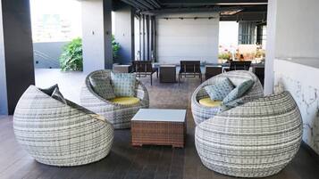 A covered outdoor seating area with wicker furniture and a central table.