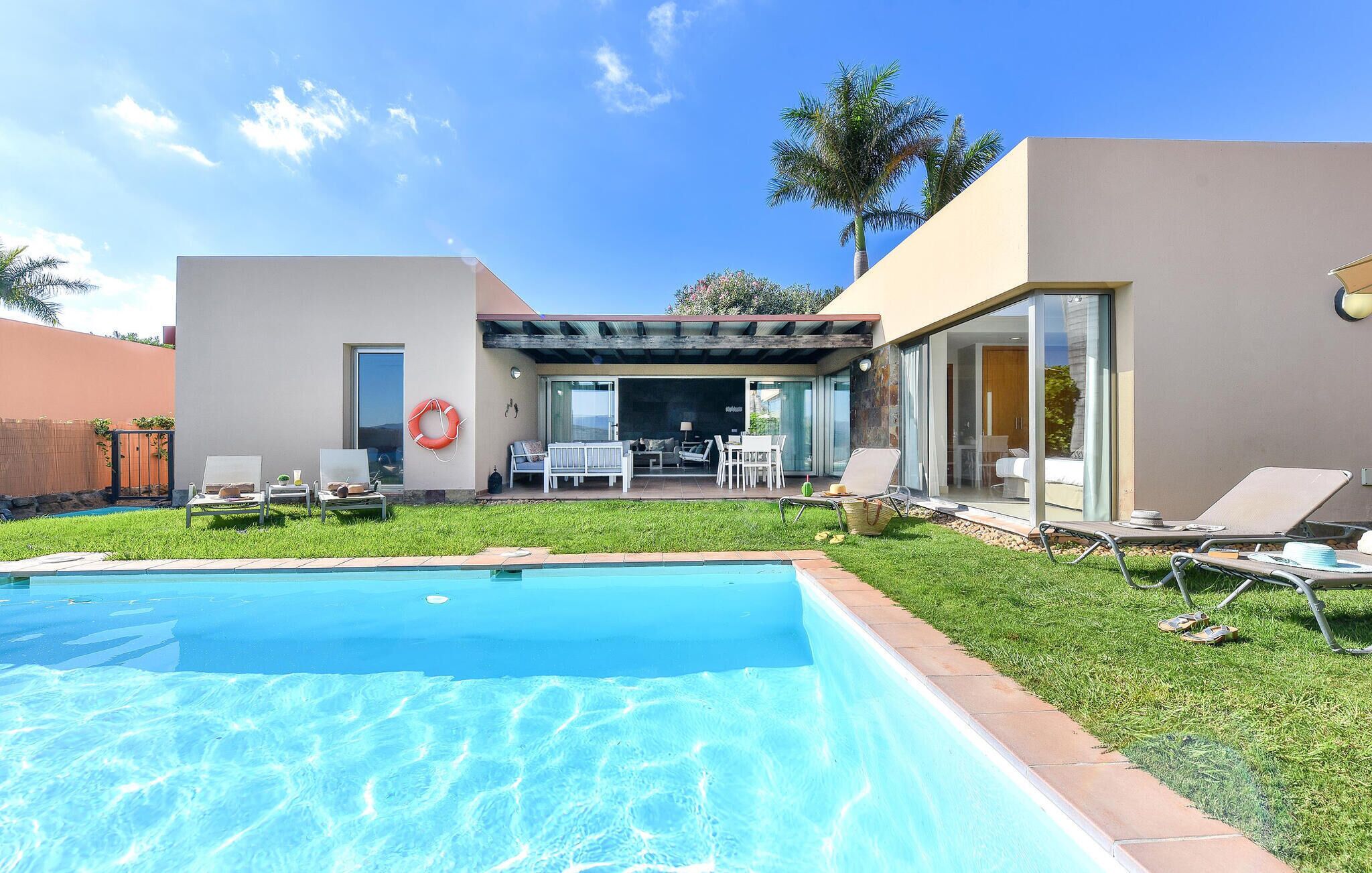 A modern house with a swimming pool, outdoor seating, and a covered patio.
