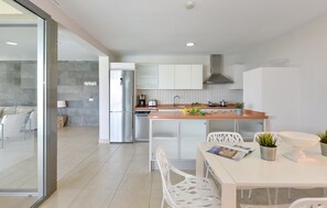 Eine moderne Küche mit einem Edelstahlkühlschrank, weißen Schränken und einer Holz Arbeitsplatte.