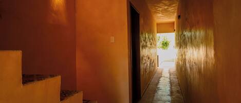 A narrow hallway with a staircase on the left and a door at the end.