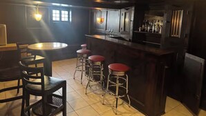 Eine Bar mit Sitzstangen, einer Theke und einer Sitzecke mit Tisch und Stühlen.