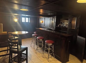 Una zona de bar con taburetes, una barra y un área de estar con una mesa y sillas.