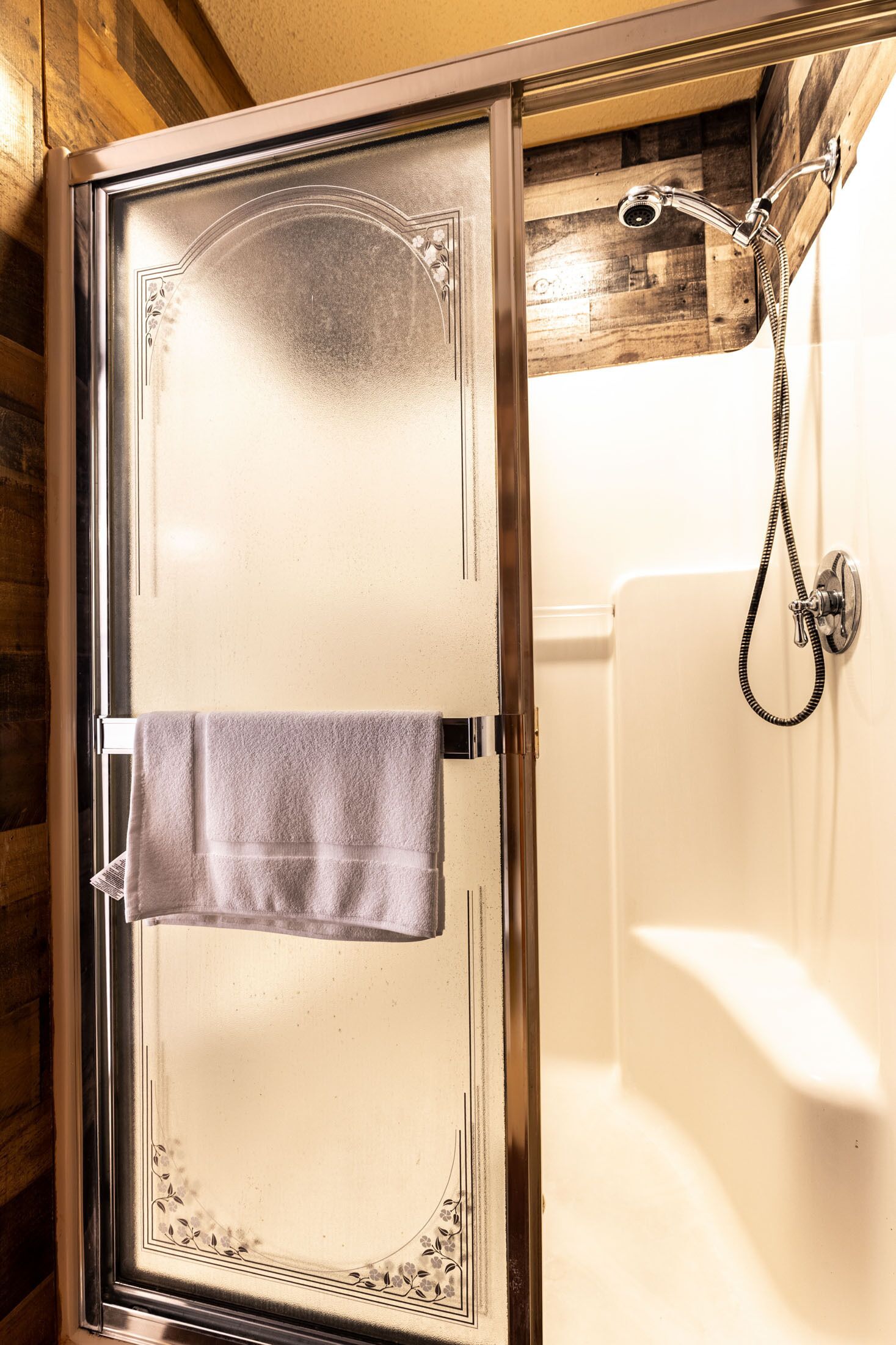 Een douche met glazen wanden en een handdoek aan de deur.