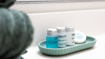 A bathroom with a white sink, a green soap dish, and two bottles of white soap.
