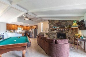 A spacious living area with a pool table, a stone fireplace, and a cozy seating area. - Mountain Forest Manor (Hiawassee)