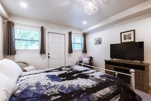Un dormitorio con cama, televisor y puerta.
