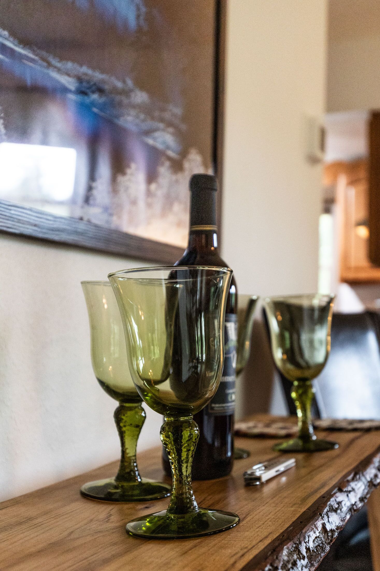 A bar area with a bottle and glasses on a wooden surface.