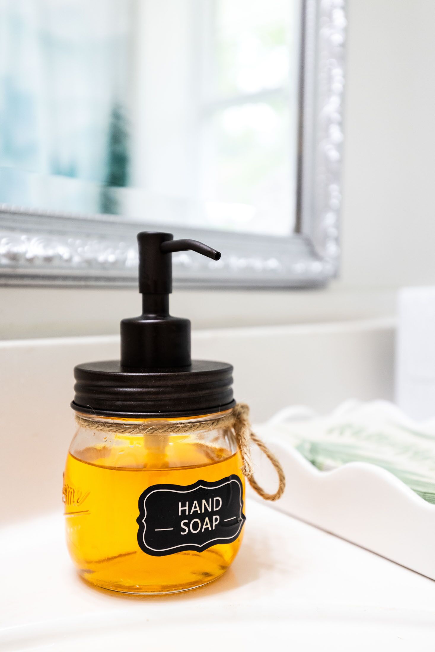 A hand soap dispenser in a jar with a pump, placed on a white surface.