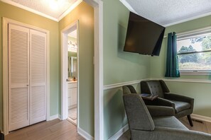 Una habitación con un armario cerrado, un televisor montado en la pared y dos sillones.