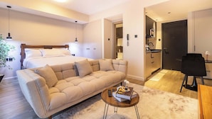 Ein modernes Hotelzimmer mit Bett, einer Couch und einer kleinen Essecke.