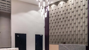 Eine moderne Lobby mit Ecksofa, Empfangstresen und Wand mit Muster.