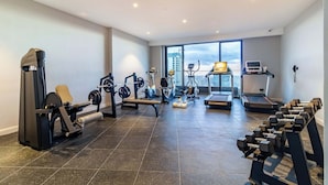 Ein Fitnessstudio mit unterschiedlichen Trainingsgeräten, Laufbändern und Kurzhanteln.
