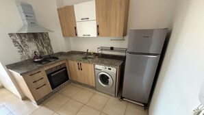 A compact kitchen with a washing machine, stainless steel refrigerator, and wooden cabinets. - Nour 5 Modern Apartment with Pool & Parking Near Train Station Central Marrakech (Marrakesh)