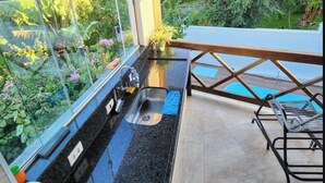 Une cuisine avec un plan de travail noir, un évier et une fenêtre donnant sur un jardin.