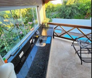 Una cocina con encimera negra, un fregadero y ventana con vistas a un jardín.