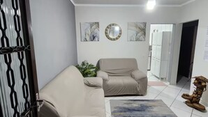 Un salon avec un canapé beige, un fauteuil, une petite table et une plante décorative.
