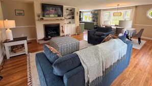 Ein Wohnzimmer mit Kamin, Sofa, Fernseher und Küchenzeile.