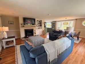 Ein Wohnzimmer mit Kamin, Sofa, Fernseher und Küchenzeile.